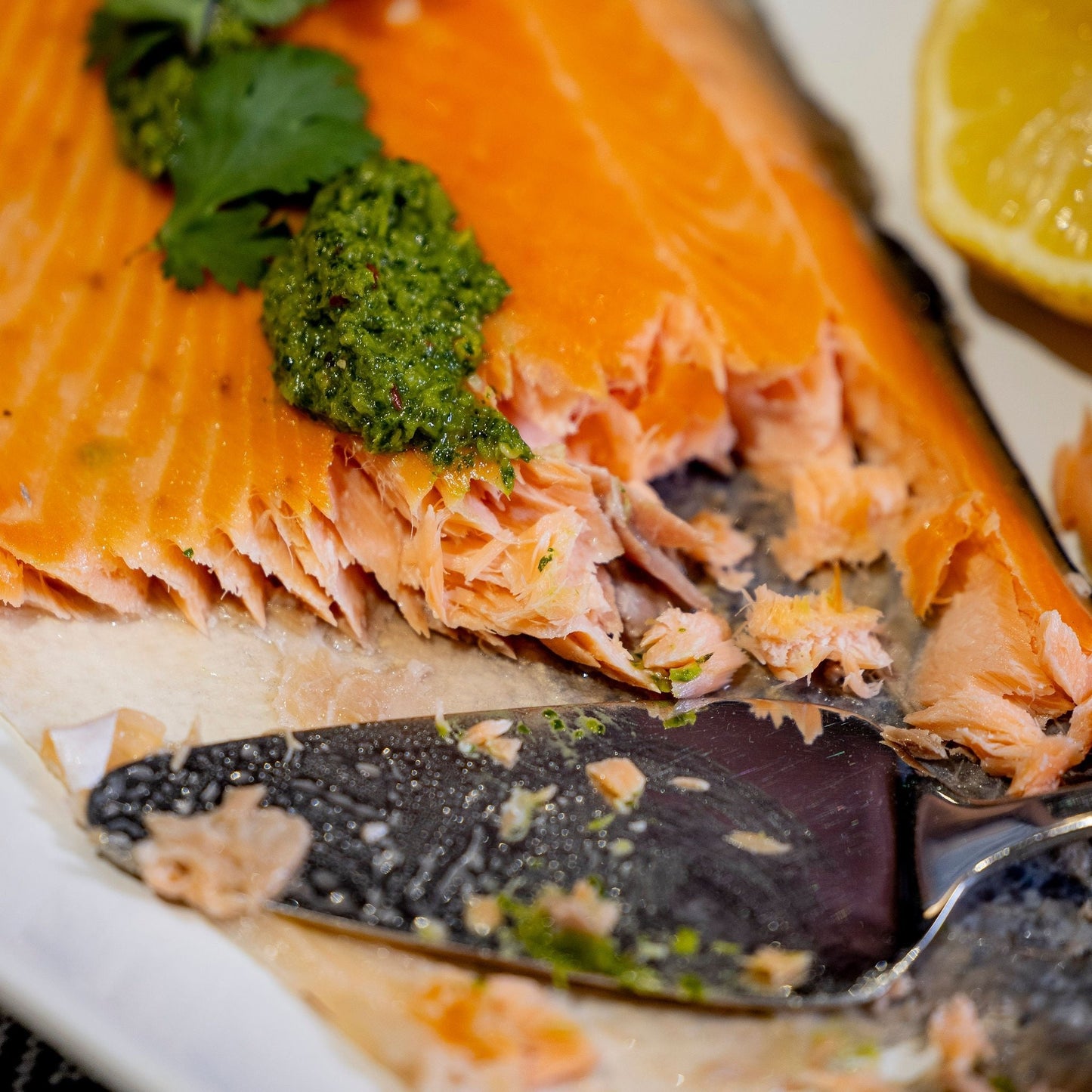 A side of salmon sits on a white platter. It has been partially served and there is a cake slide on the platter.