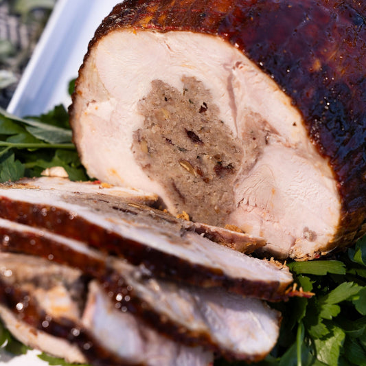 A turkey breast roll is sliced and sitting on a platter.