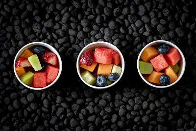 Three fruit salad cups on a black background