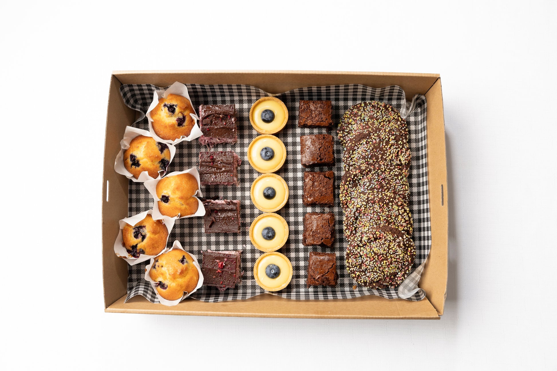 A box of Chocolate Brownie, Lemon Curd Tarts with Blueberry, Raspberry Ripe Slice, Chocolate Sprinkle Biscuits, & Blueberry Mini Muffins